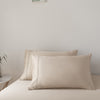 Beige bamboo pillows on a bed against a plain wall
