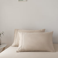 Beige bamboo pillows on a bed against a plain wall