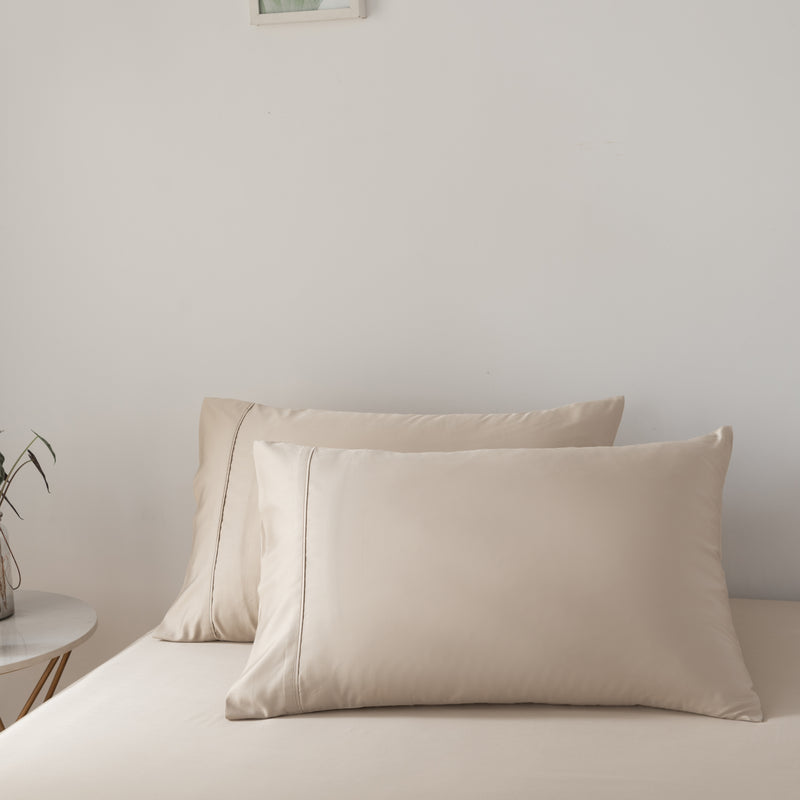 Beige bamboo pillows on a bed against a plain wall