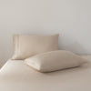 Two beige bamboo pillows on a bed against a plain background