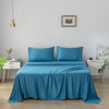 Blue bamboo sheet set on a bed in a bedroom with white walls and minimal decor.