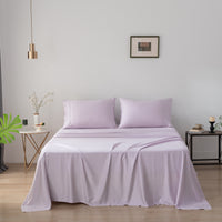 Purple bamboo bedding set on a bed in a bedroom with a lamp and decor items.