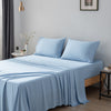 Blue bamboo bed sheets and pillows on a bed in a bedroom setting.